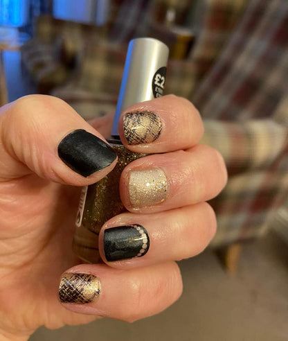 Hand wearing black gold glitter textured nail wraps on short nails