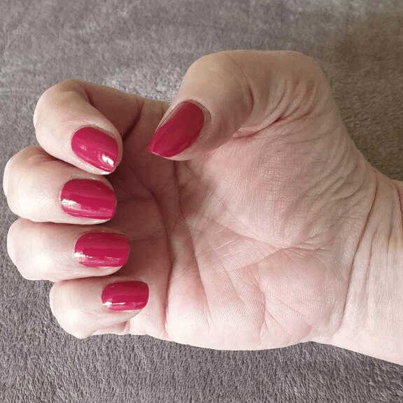 Bright pink glossy nail wraps on hand showing vibrant manicure finish