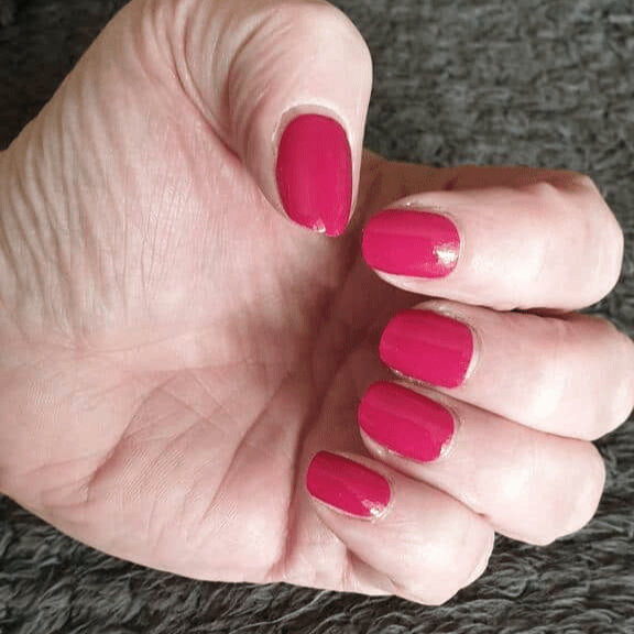 Hot pink gel nail wraps on hand displaying smooth glossy manicure