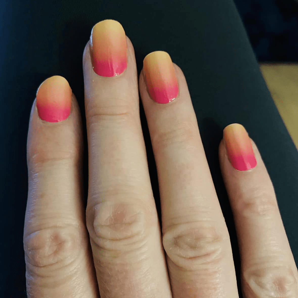 Hand wearing pink and yellow ombre nail wraps with glossy finish