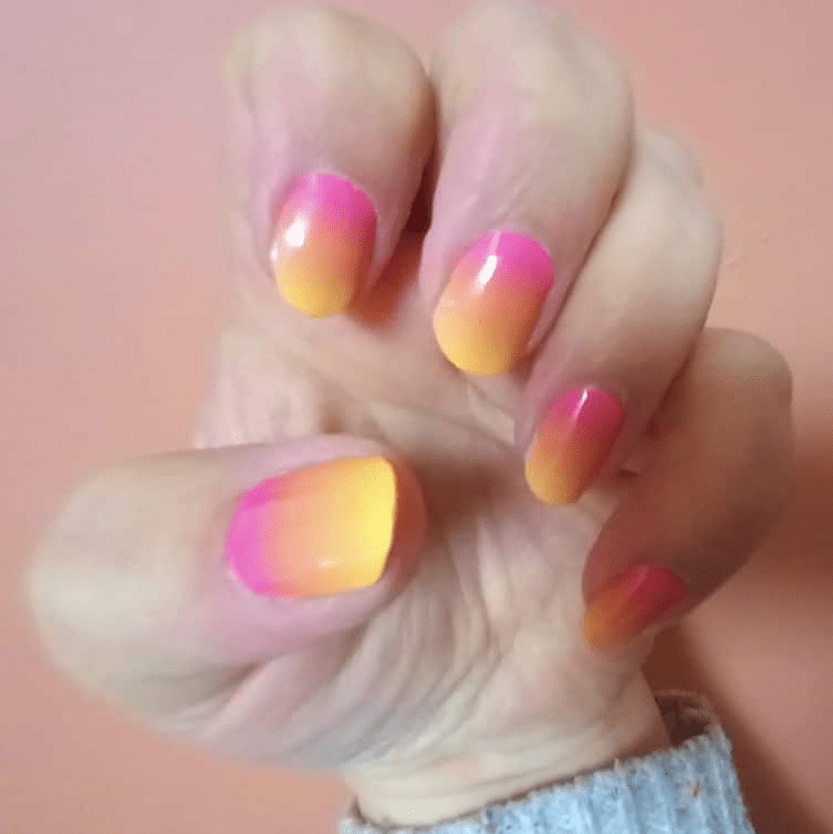 Sunset gradient nail wraps on hand showing pink orange yellow ombre design