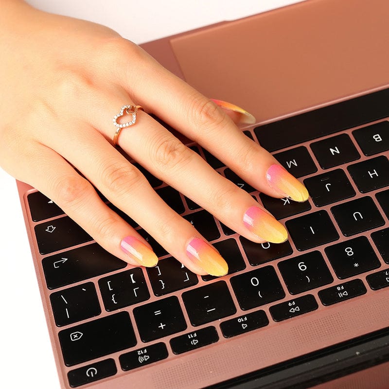 Hand typing on laptop wearing vibrant sunset ombre nail wraps