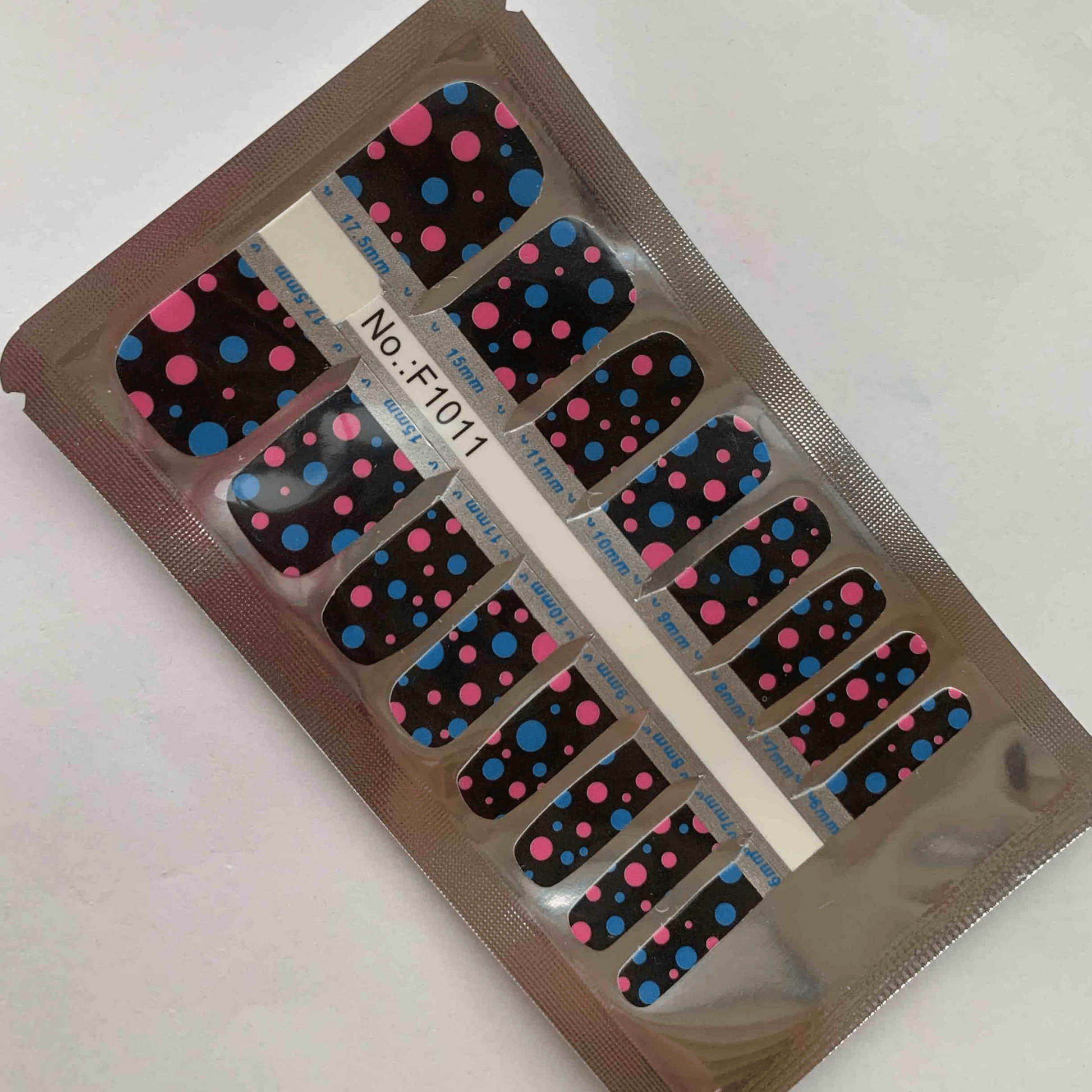 Packaged pedicure nail wraps with black and multicoloured polka dot design