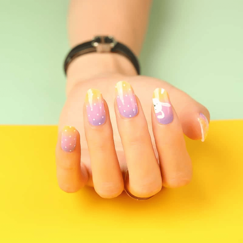 Purple and orange gradient nail wraps with white bunny pattern on hand