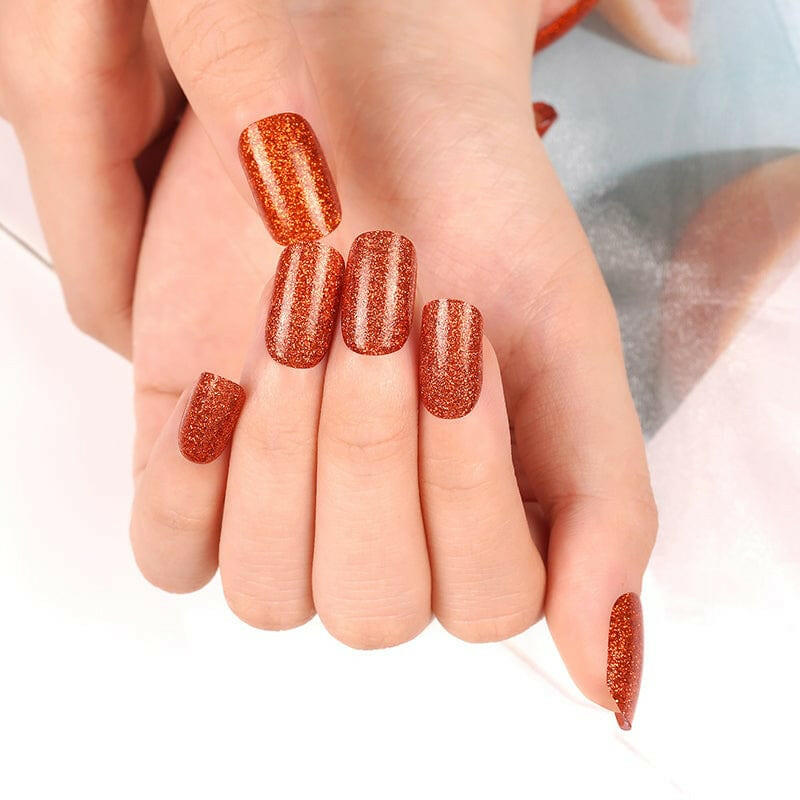 Two hands showcasing burnt sienna metallic glitter nail wraps in copper shade