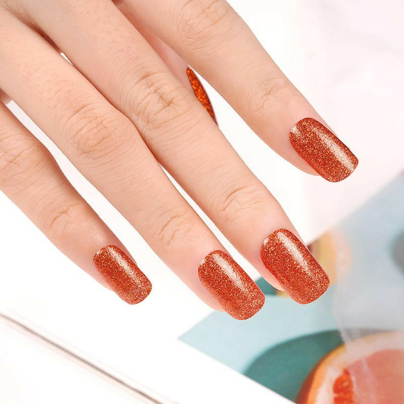 Orange glitter nail wraps on hand displaying sparkly burnt sienna gel nail art