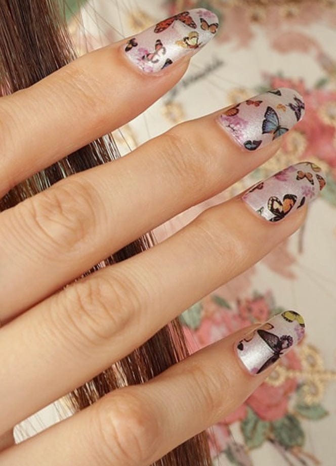 Hand wearing butterfly nail wraps showing delicate colourful butterfly pattern manicure design