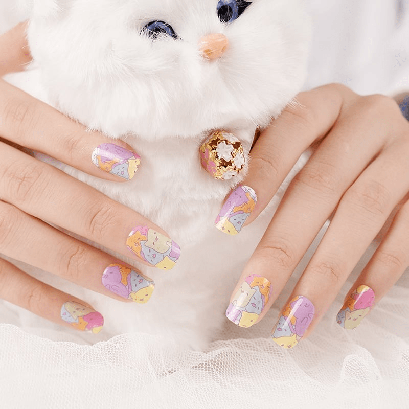Hands with cat pattern nail art wraps in purple yellow holding white fluffy cat