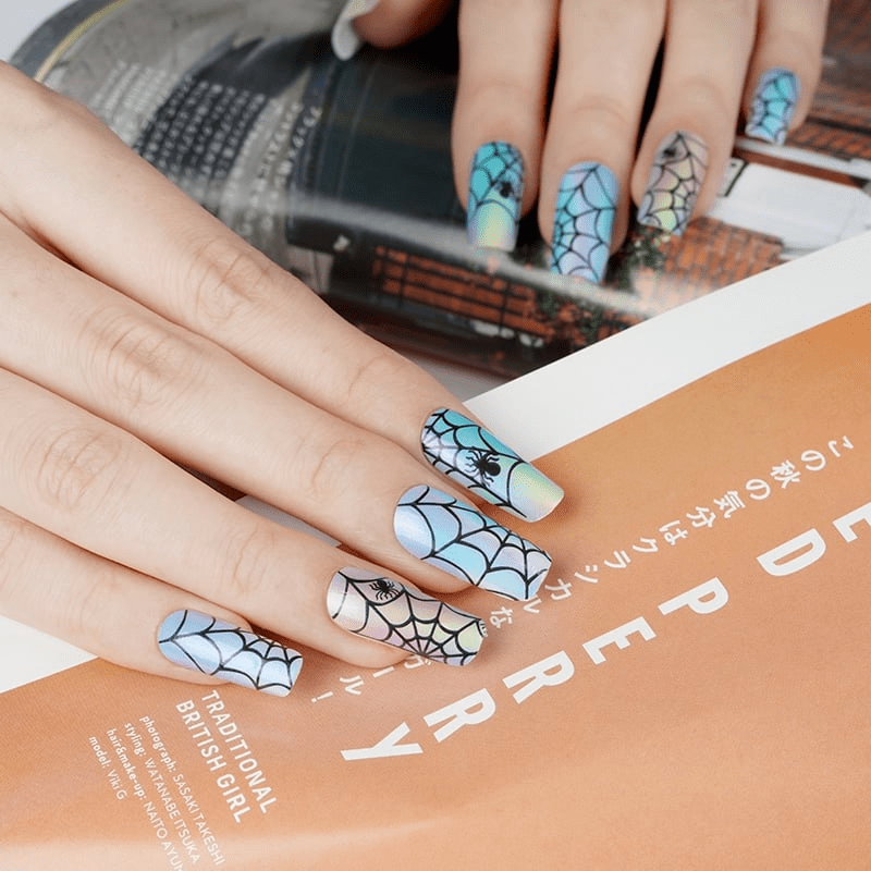Spider web gel nail wraps applied on hand showing holographic blue gothic Halloween manicure