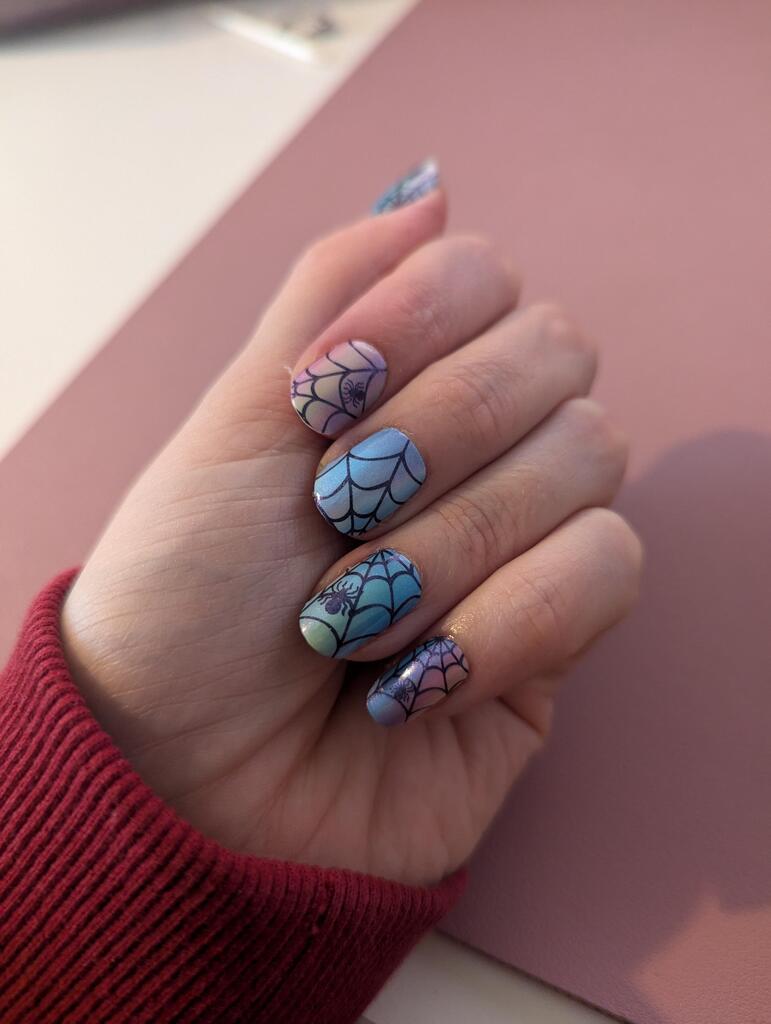 Hand wearing holographic spider web nail wraps with iridescent rainbow finish