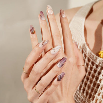 Purple watercolour nail wraps with gold details on manicured hands showing nail art design