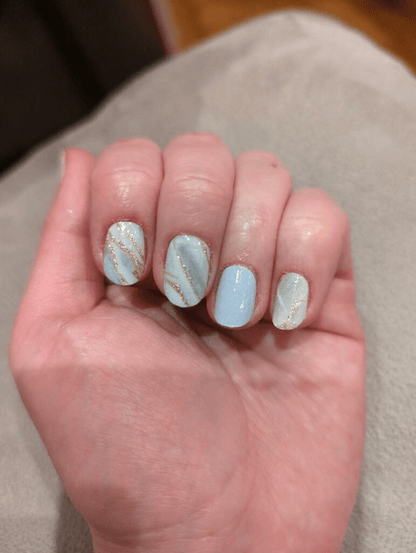 Blue and white marble nail wraps with gold veining on hand showing nail art design