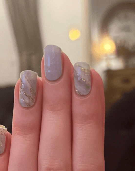 Grey and white marble nail wraps with gold accents creating elegant manicure effect