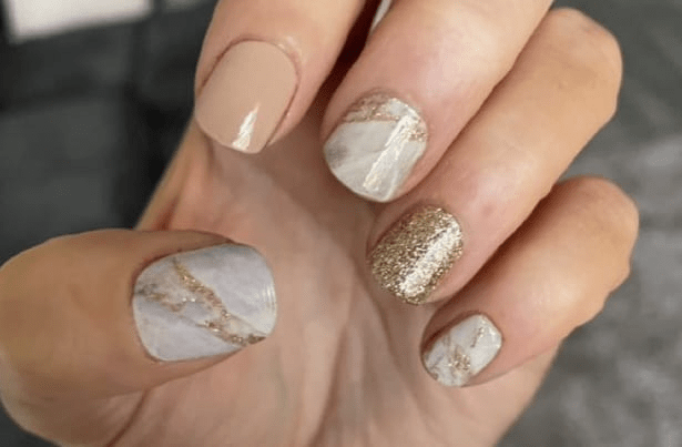 White marble nail wraps with gold glitter accents on natural nails at-home manicure