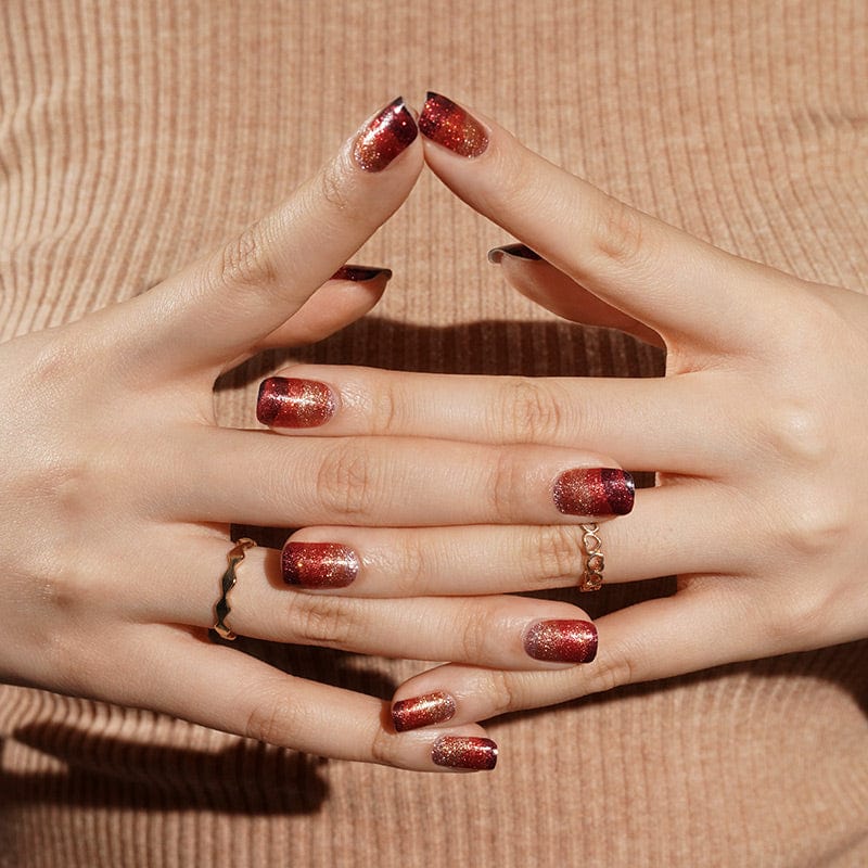 Hands with red to black gradient glitter nail wraps in interlocked finger pose