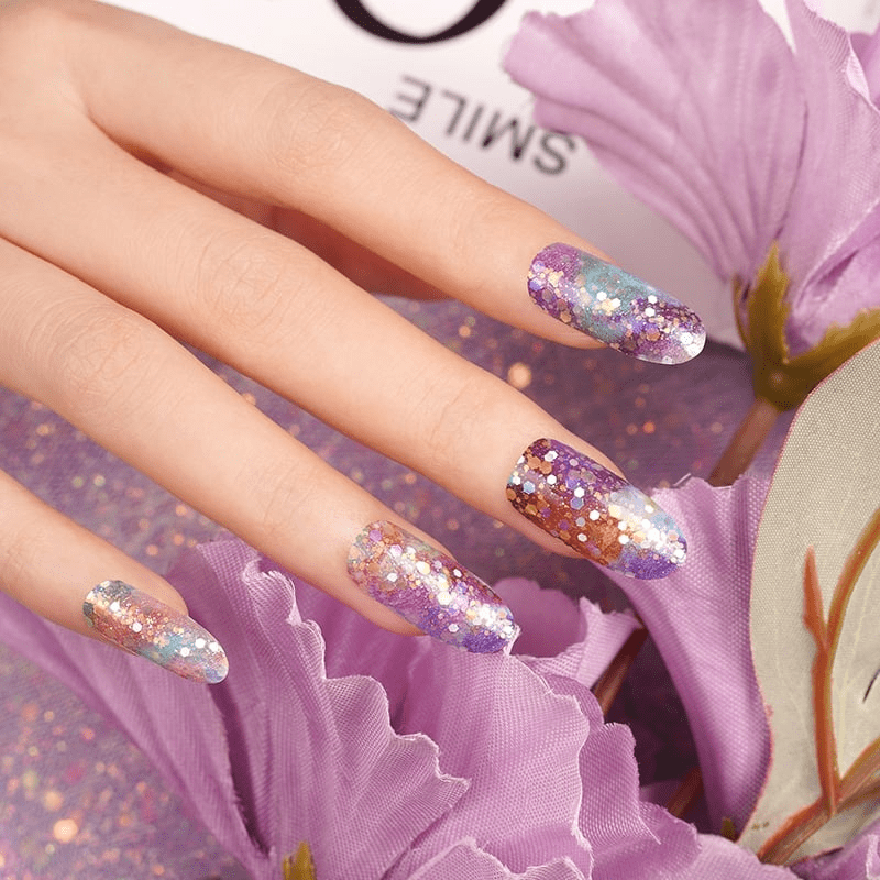 Purple glitter gel nail wraps with iridescent sparkles on hand with pink flowers