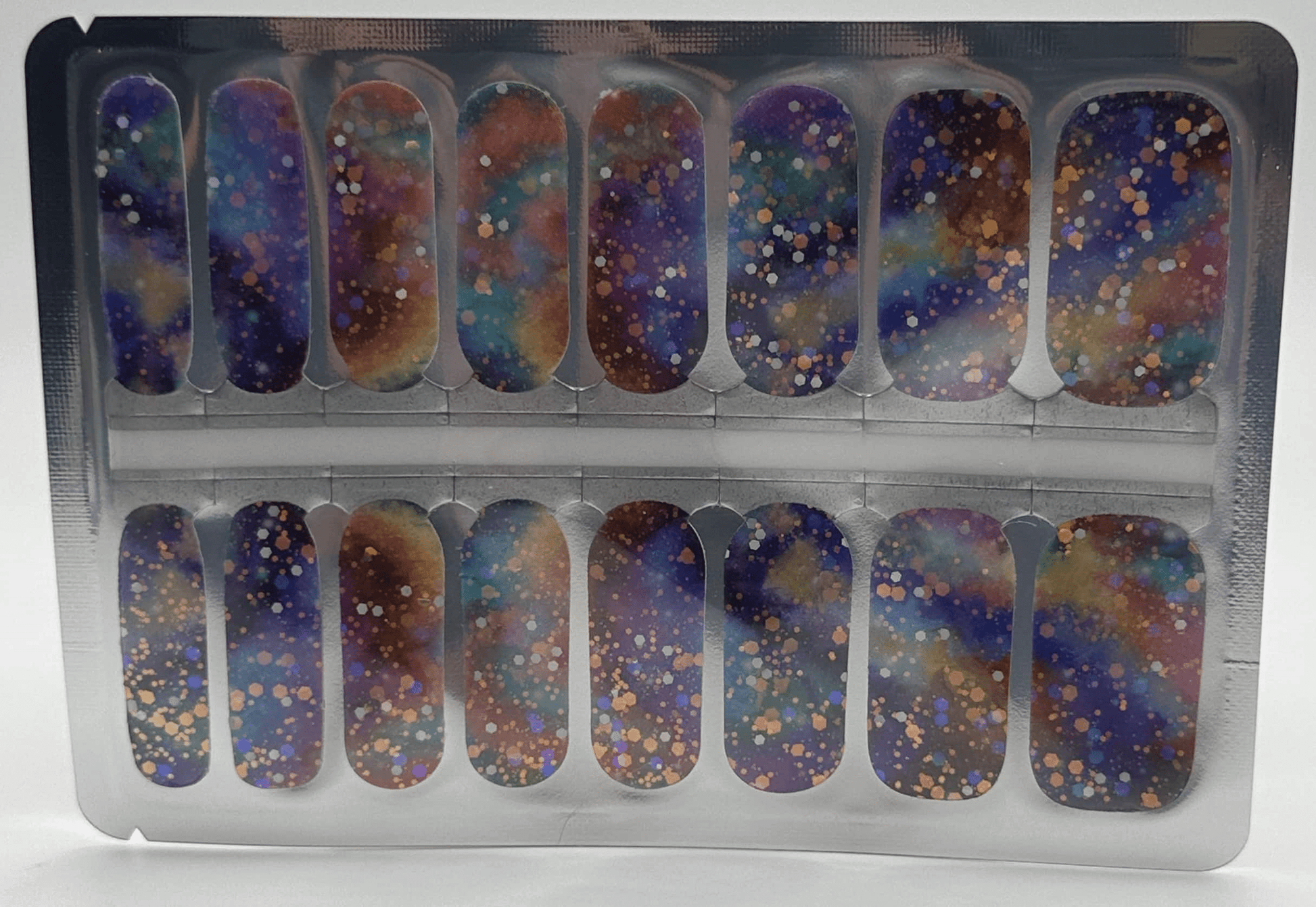 Cosmic glitter nail wraps in packaging featuring purple blue gold sparkle nail art