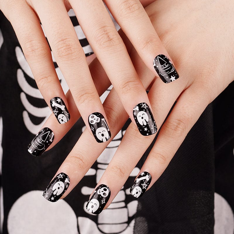 Gothic glow-in-the-dark nail wraps featuring skull designs on hands against black background