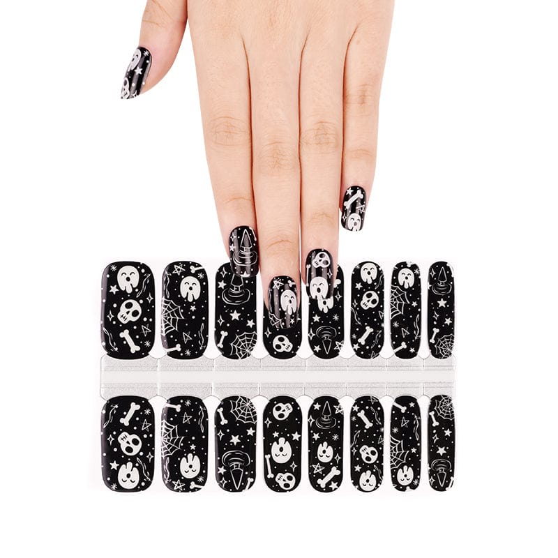 Black Halloween nail wraps with white skull and bone gothic patterns on hand