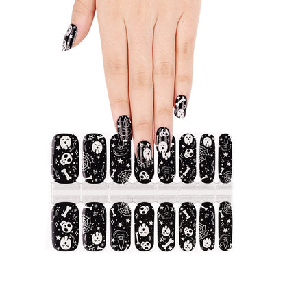 Black Halloween nail wraps with white skull and bone gothic patterns on hand