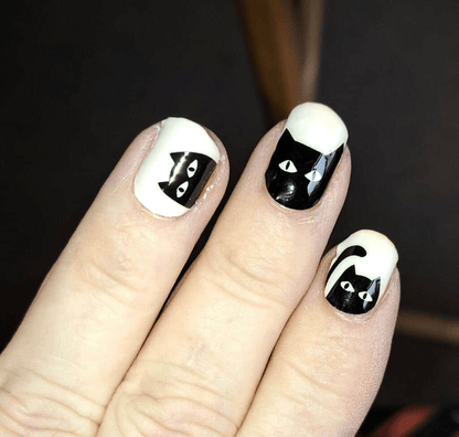 White nail wraps with black cat faces on hand showing sunlight-sensitive colour-changing design
