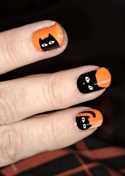 Orange nail wraps with black cat silhouettes on hand featuring sunlight-sensitive colour-changing technology