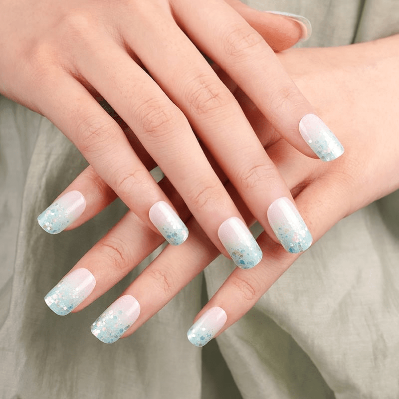 Pastel blue and pink glitter nail wraps on hands showing sparkly gradient manicure