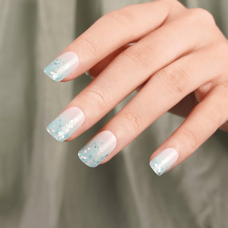 Sparkly blue and pink nail wraps on fingertips showing glittery ombre manicure