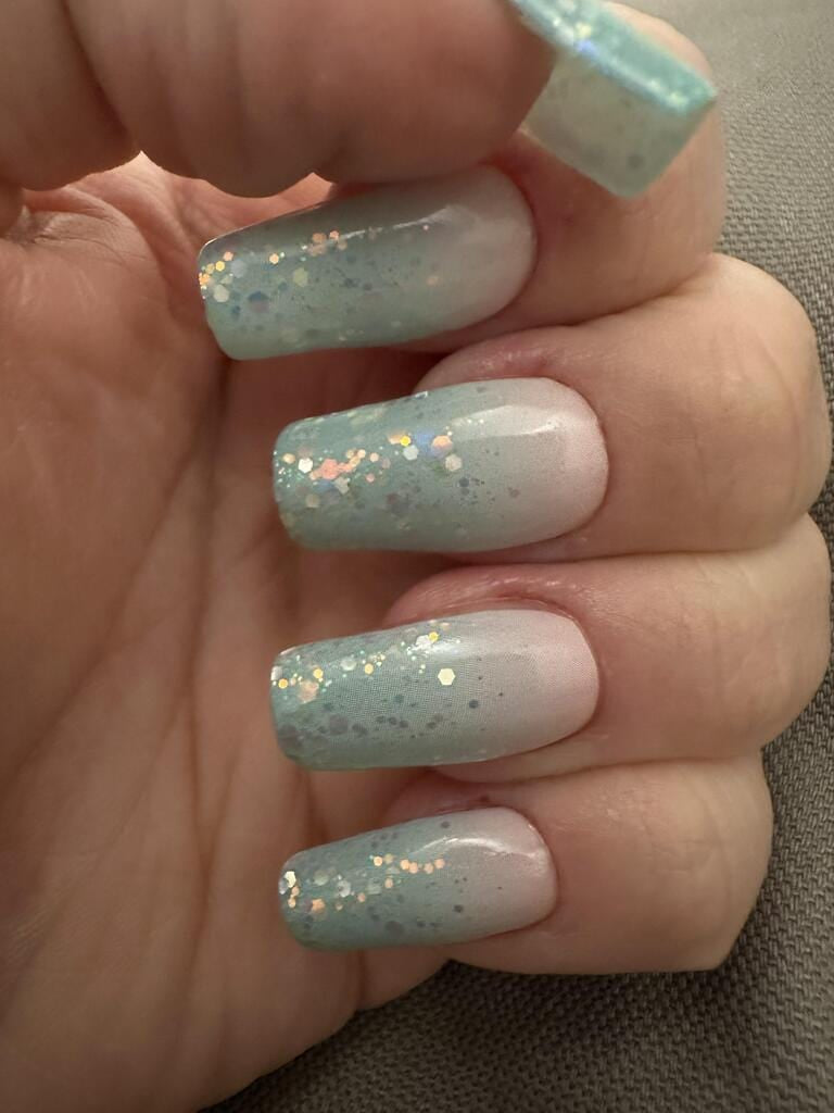 Blue ombré glitter nail wraps applied on hand showing iridescent sparkle finish