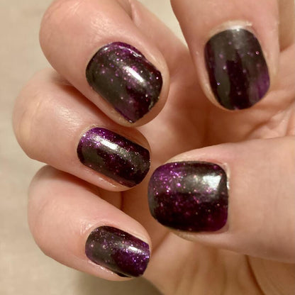 Purple cosmic nail wraps applied on hand showing glittery star pattern finish