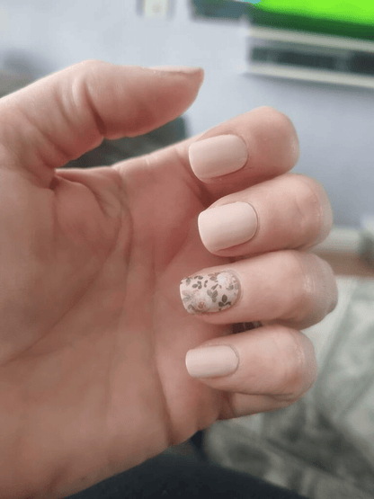 Hand wearing nude nail wraps with delicate floral botanical design on accent nails