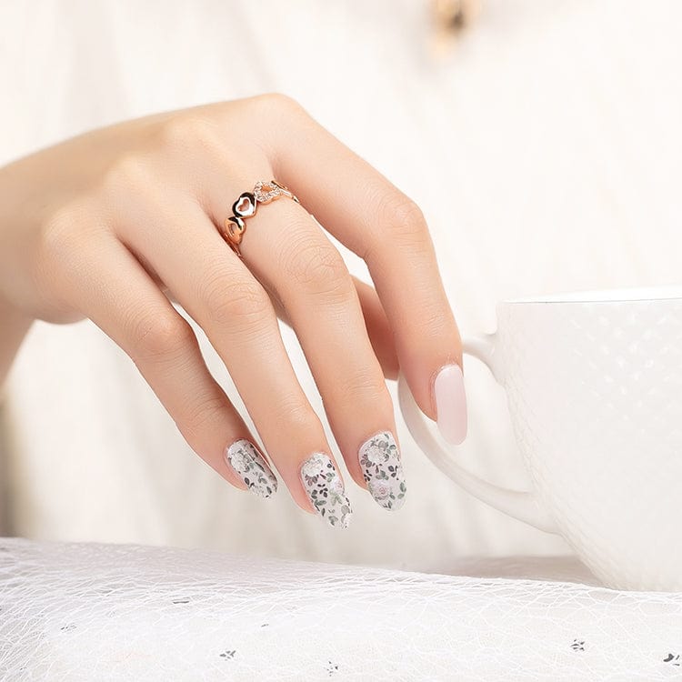 Elegant manicure featuring nude nails with floral nail art wraps on accent fingers