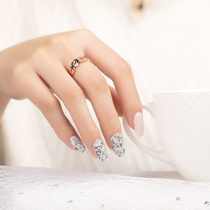 Elegant manicure featuring nude nails with floral nail art wraps on accent fingers