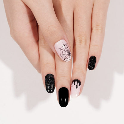 Manicured nails with Halloween nail wraps featuring black glitter and pink spider web art