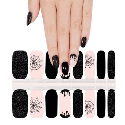Hand applying Halloween nail wraps with black and pink gothic spider designs
