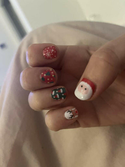 Festive nail art on fingers featuring Santa Claus, reindeer and red green Christmas patterns