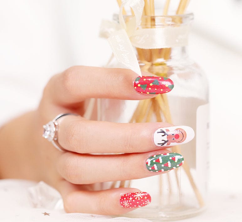 Christmas nail wraps on hand showing red snowflake, Santa, reindeer and green holly patterns