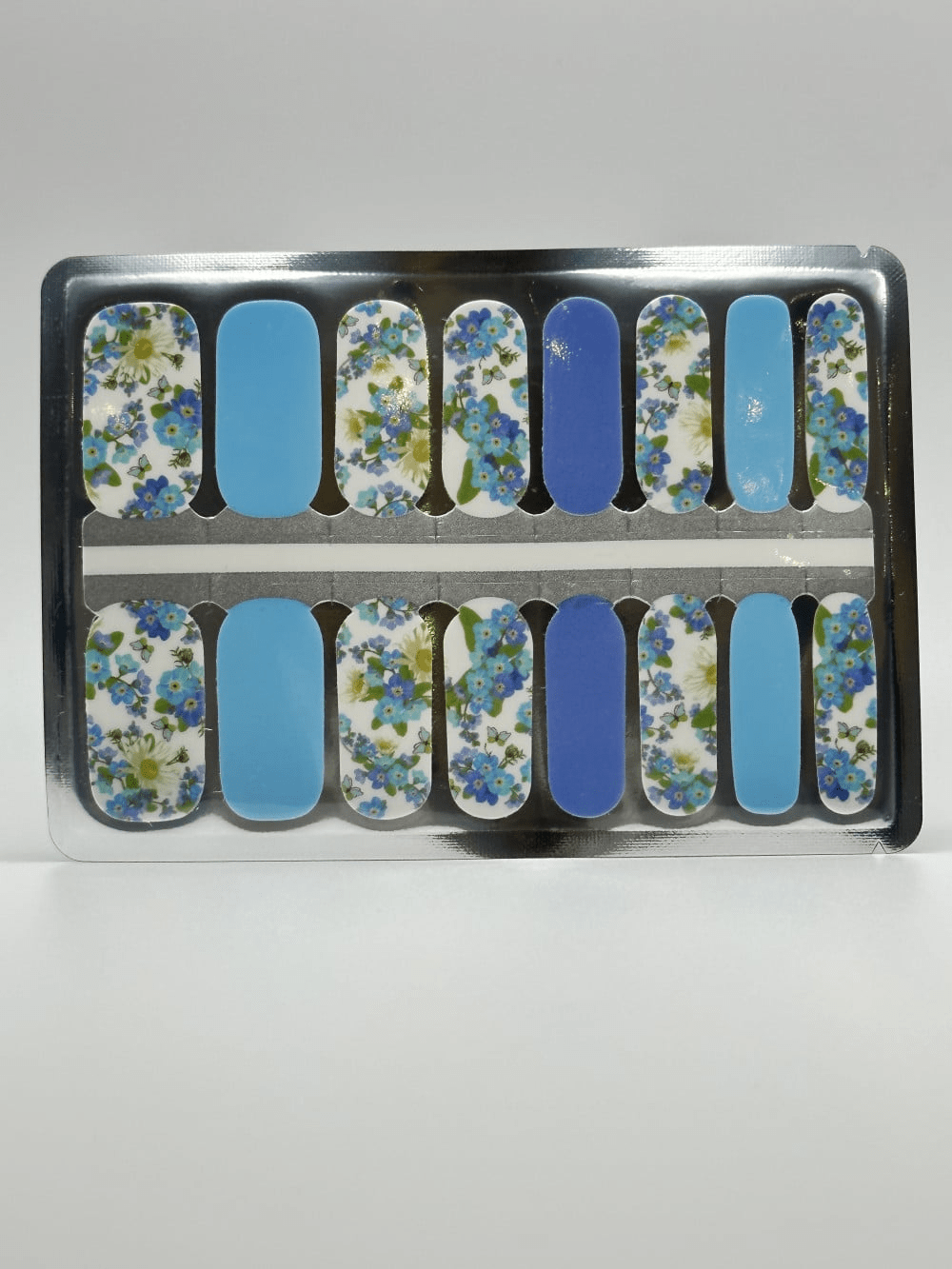 Blue and white daisy nail wrap strips in packaging showing floral pattern designs