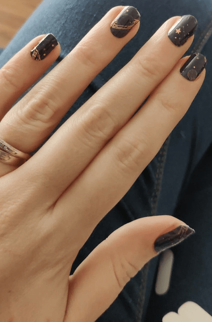 Deep space gel nail wraps featuring gold stars and planets on dark blue background