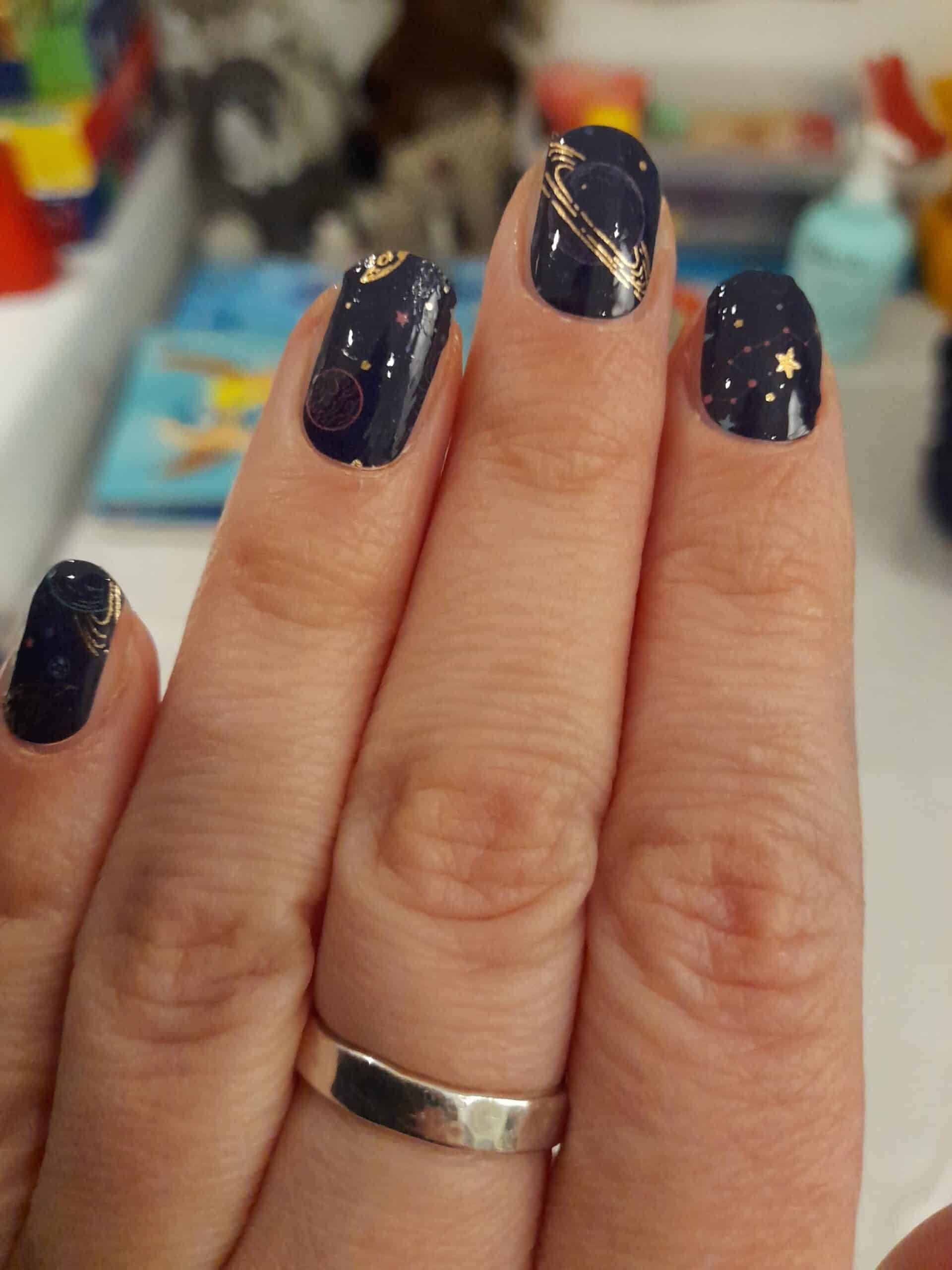 Celestial nail art wraps in navy blue with metallic gold star and planet design
