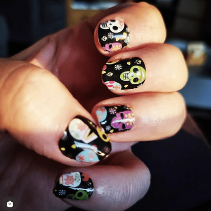 Black gothic nail wraps with colourful Day of the Dead skulls and floral patterns on hand