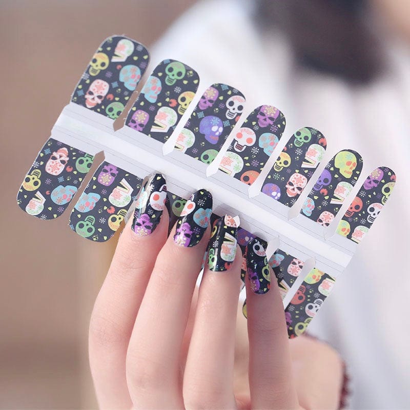 Hand wearing Day of the Dead gel nail wraps with colourful skull art design