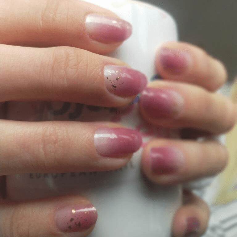 Pink gradient gel nail wraps with glitter accents on hands at-home manicure