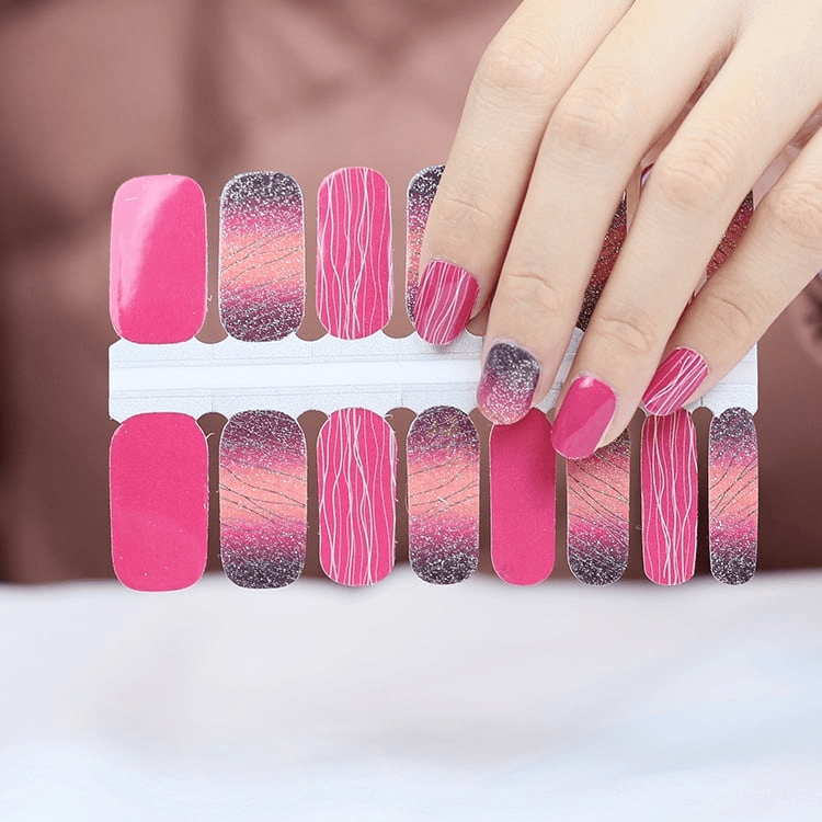 Pink and glitter nail wraps with diagonal stripe pattern displayed on sheet and hand