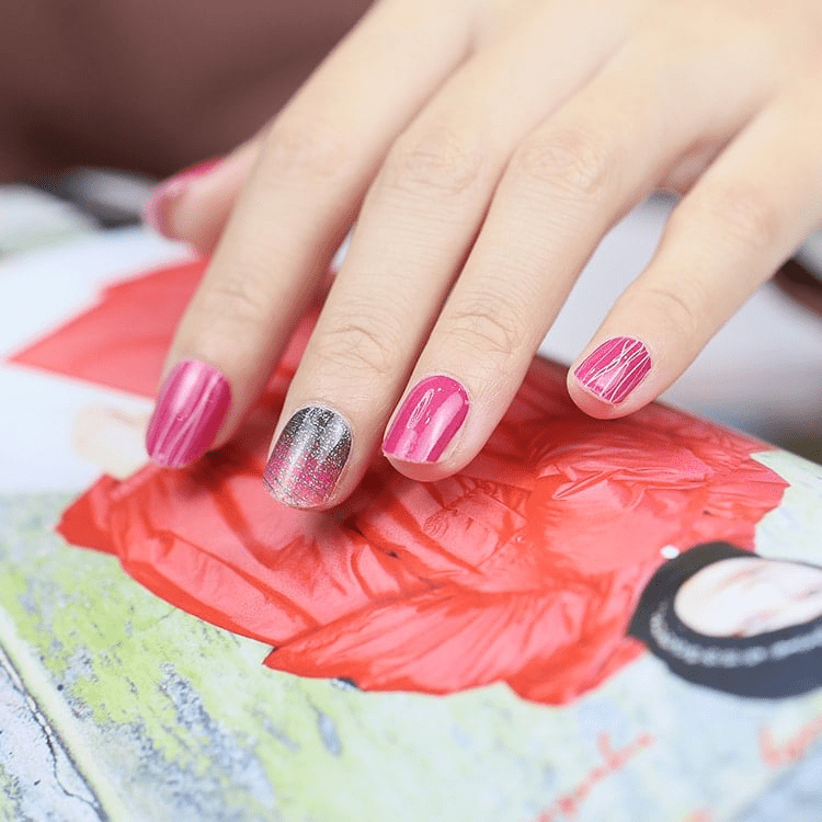 Hand wearing pink and silver glitter diagonal stripe gel nail wraps on art palette