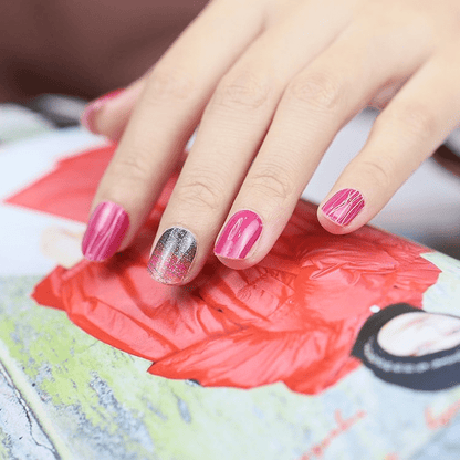 Hand wearing pink and silver glitter diagonal stripe gel nail wraps on art palette