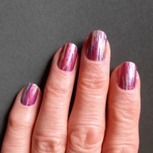Hand wearing pink purple chrome nail wraps with vertical stripe finish