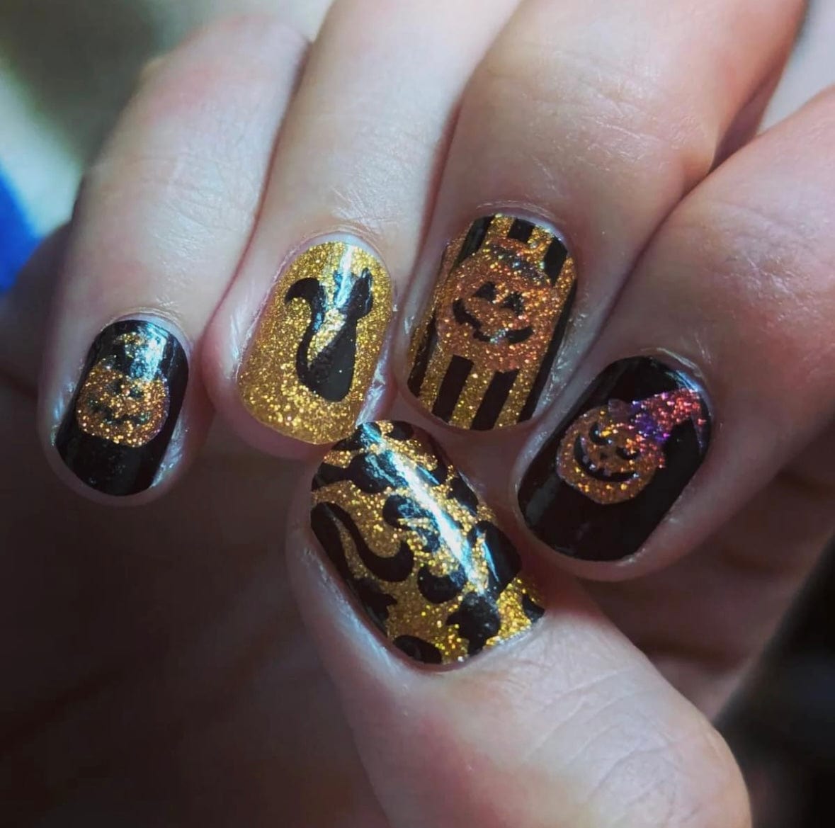 Halloween glitter nail wraps on hand with orange black pumpkin spooky designs