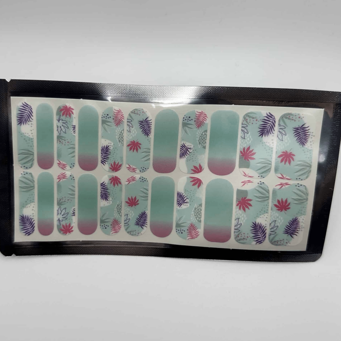 Sheet of tropical nail wraps showing turquoise base with coral and purple palm leaf designs