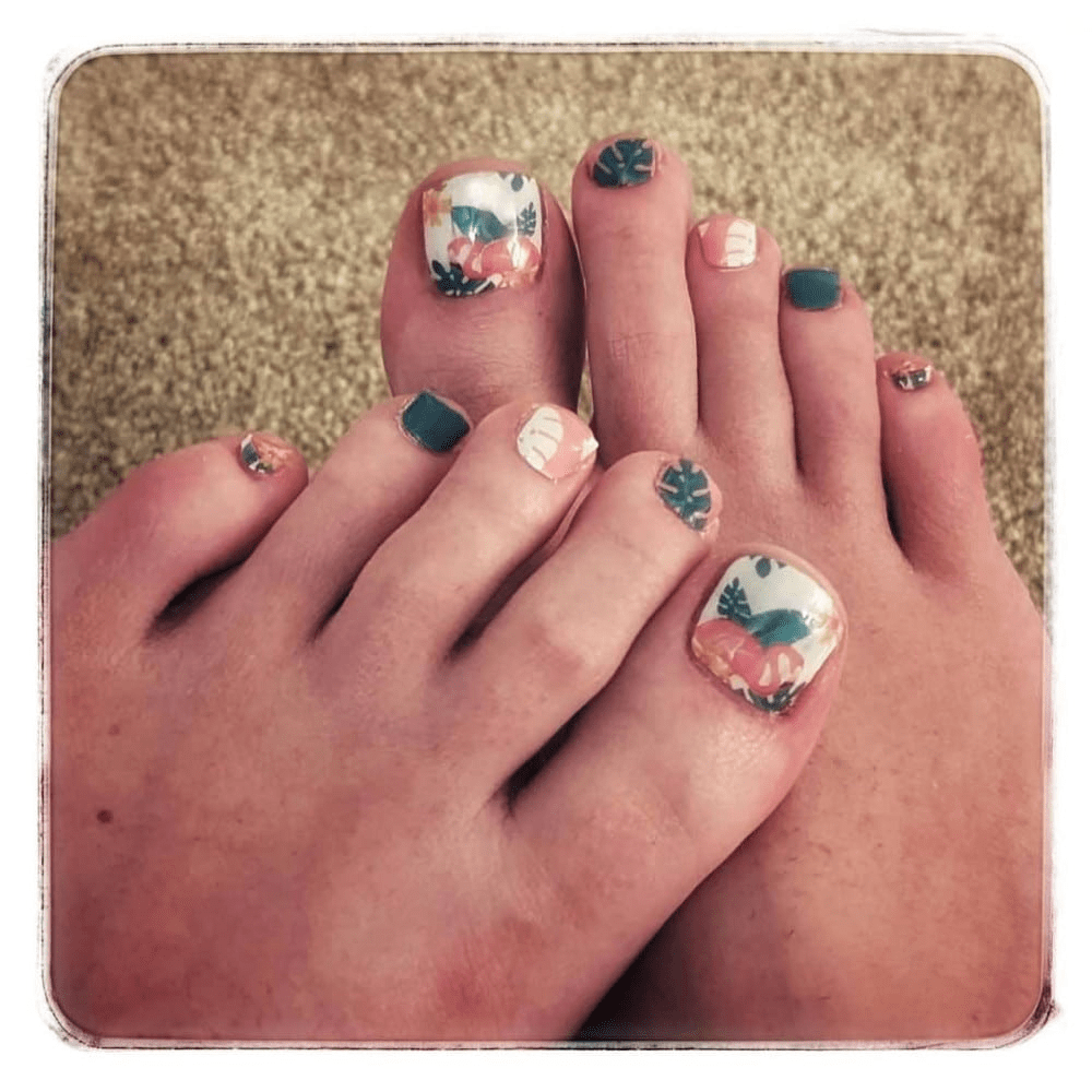 Tropical flamingo pedicure nail wraps applied on feet showing coral and teal design